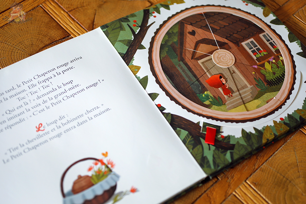 Kapturek u drzwi babci; przesunięcie czerwonego uchwytu obraca koło i zmienia ujęcie sceny. Wydanie francuskie Fleurus z ilustracjami Emilii Dziubak.