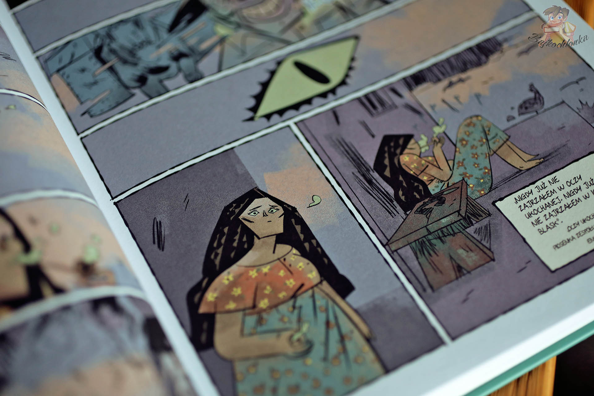 Bohaterka w domowym wnętrzu; symboliczne oko w kadrze – emocjonalna scena z komiksu.