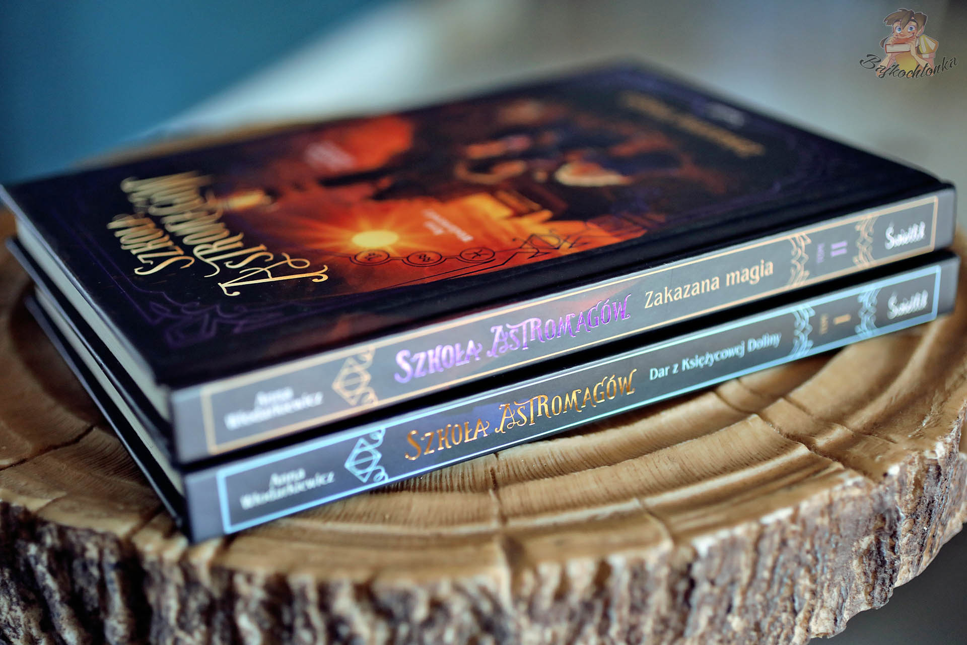 Szkoła Astromagów – grzbiety tomów: Zakazana magia i Dar z Ksiezycowej Doliny na drewnianym pniu