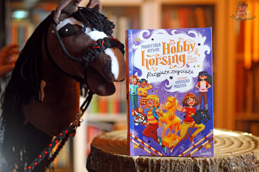 Okładka trzeciego tomu serii Hobby horsing, czyli przyjaźń w galopie ustawiona przy hobby horsie; autorka Małgorzata Korbiel.