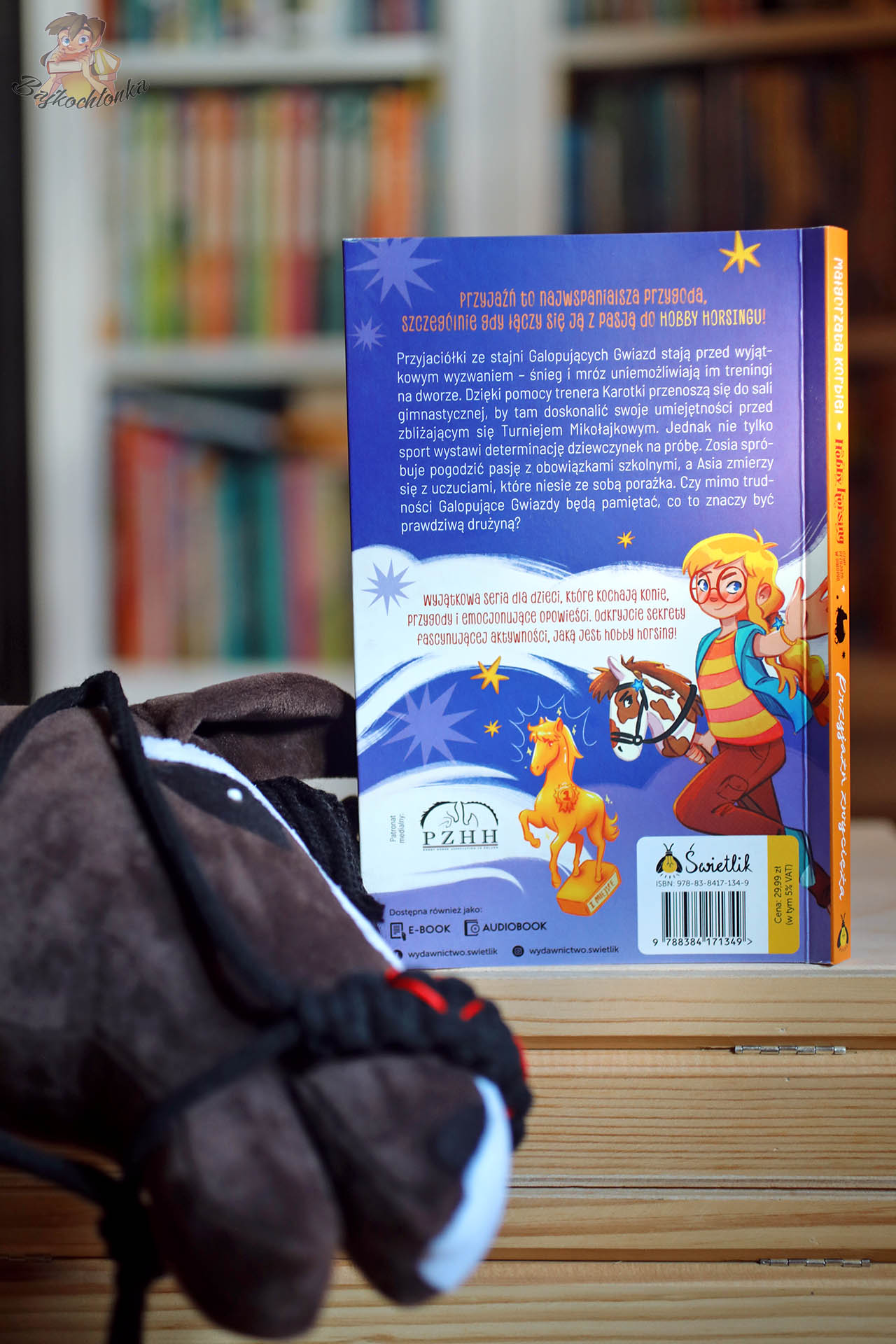 ylna okładka tomu Przyjaźń zwycięża z opisem serii i logotypami; na pierwszym planie pluszowy hobby horse.