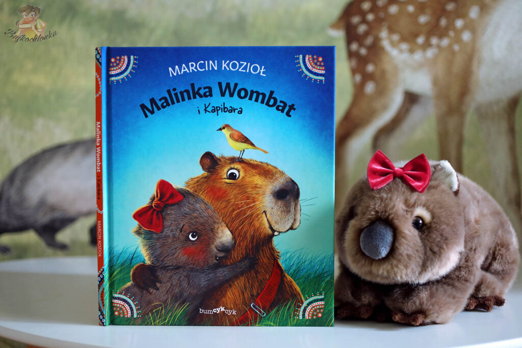 Okładka Malinka Wombat i Kapibara – Marcin Kozioł, Bumcykcyk – pluszowy wombat obok książki