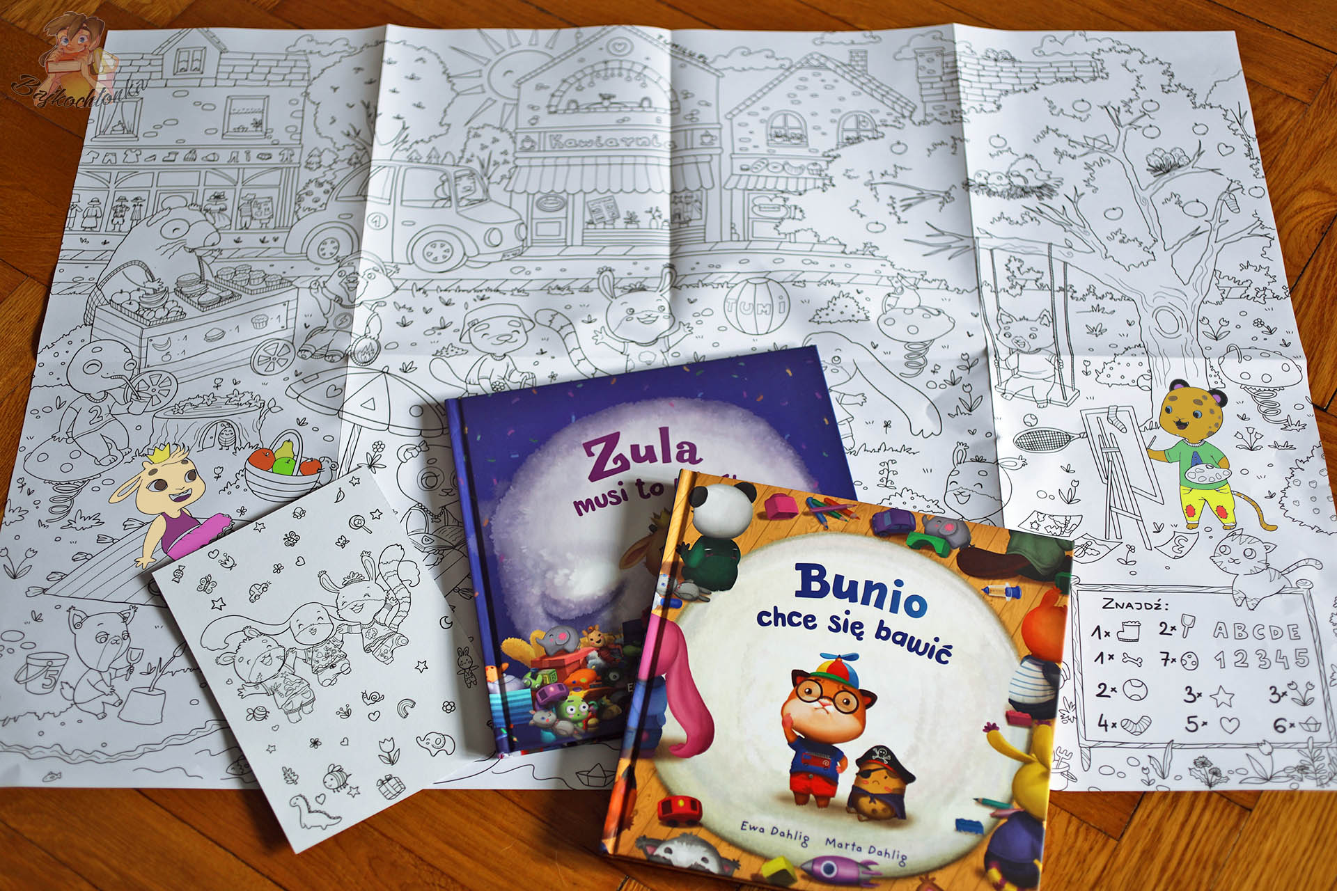 Gigaformatowa kolorowanka z Doliny Tumilu rozłożona na podłodze oraz książki „Bunio chce się bawić” i „Zula musi to mieć” – recenzja serii dla dzieci 3–7 lat.