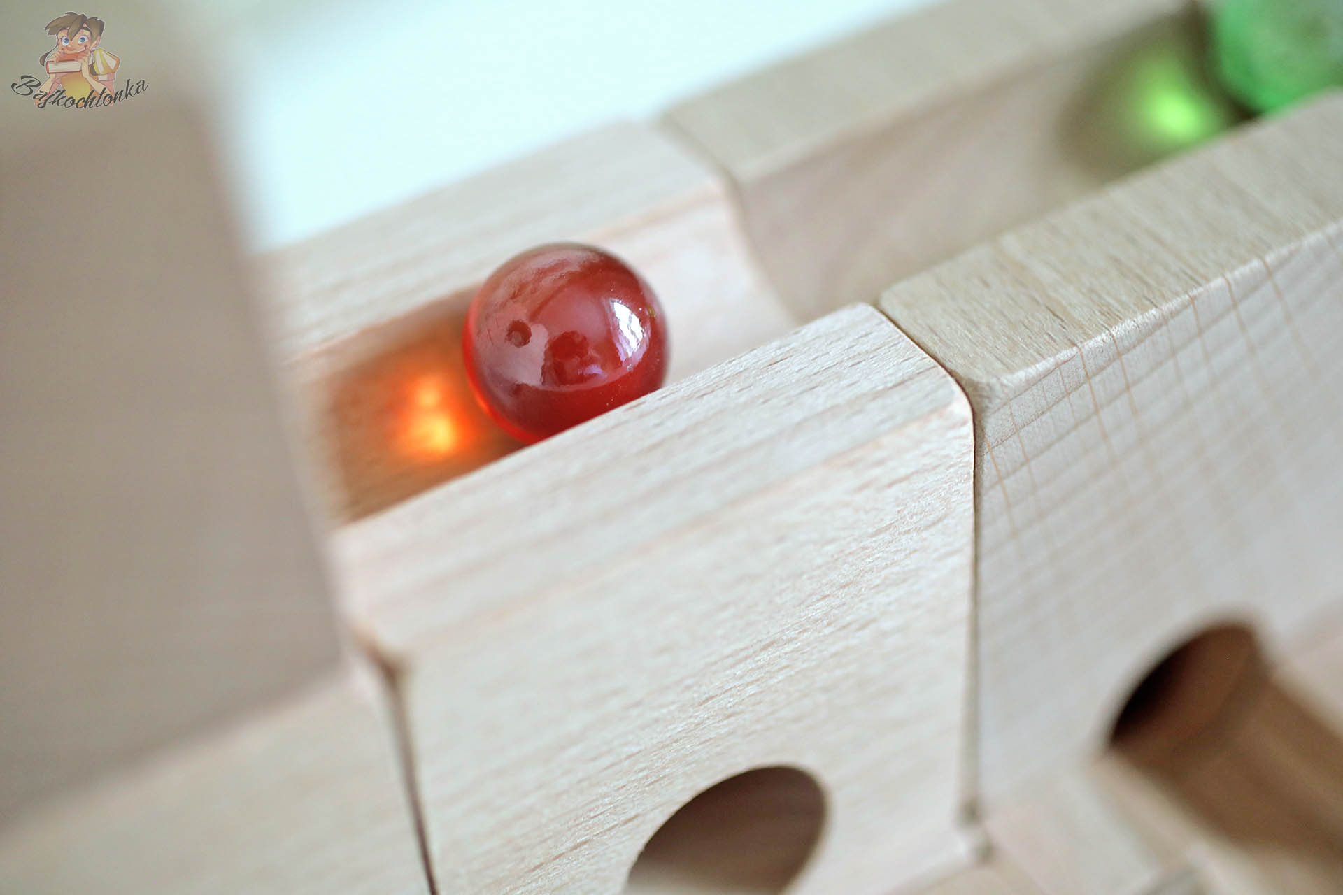 Czerwona szklana kulka na prostym odcinku drewnianego toru kulkowego Cuboro Magnet