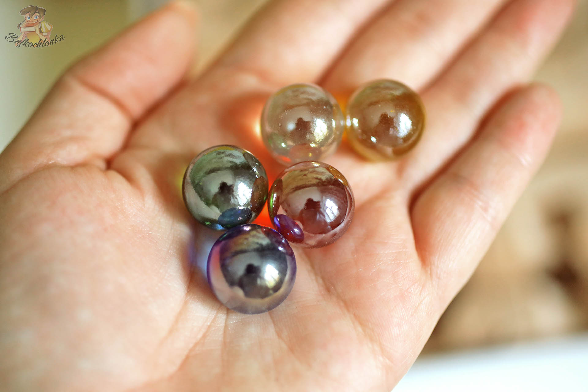 Pięć kolorowych szklanych kulek z zestawu Cuboro Magnet trzymanych w dłoni