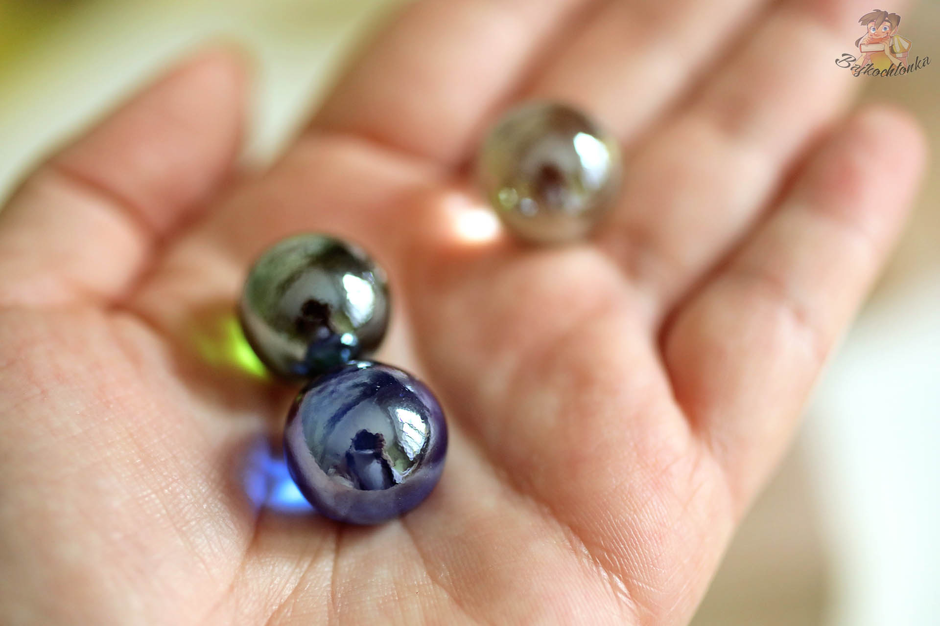 Kolorowe szklane i metalowe kulki z zestawu Cuboro Magnet trzymane na dłoni