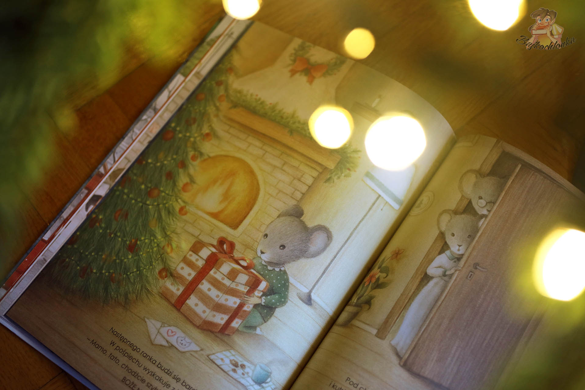 ilustracja z książki Gwiazdka Myszki myszka przy kominku otwiera świąteczny prezent pod choinką