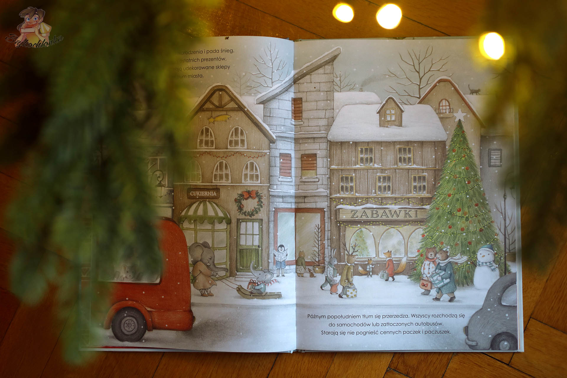 rozłożona książka Gwiazdka Myszki z ilustracją zimowego miasta, sklepu z zabawkami i dużej choinki na placu