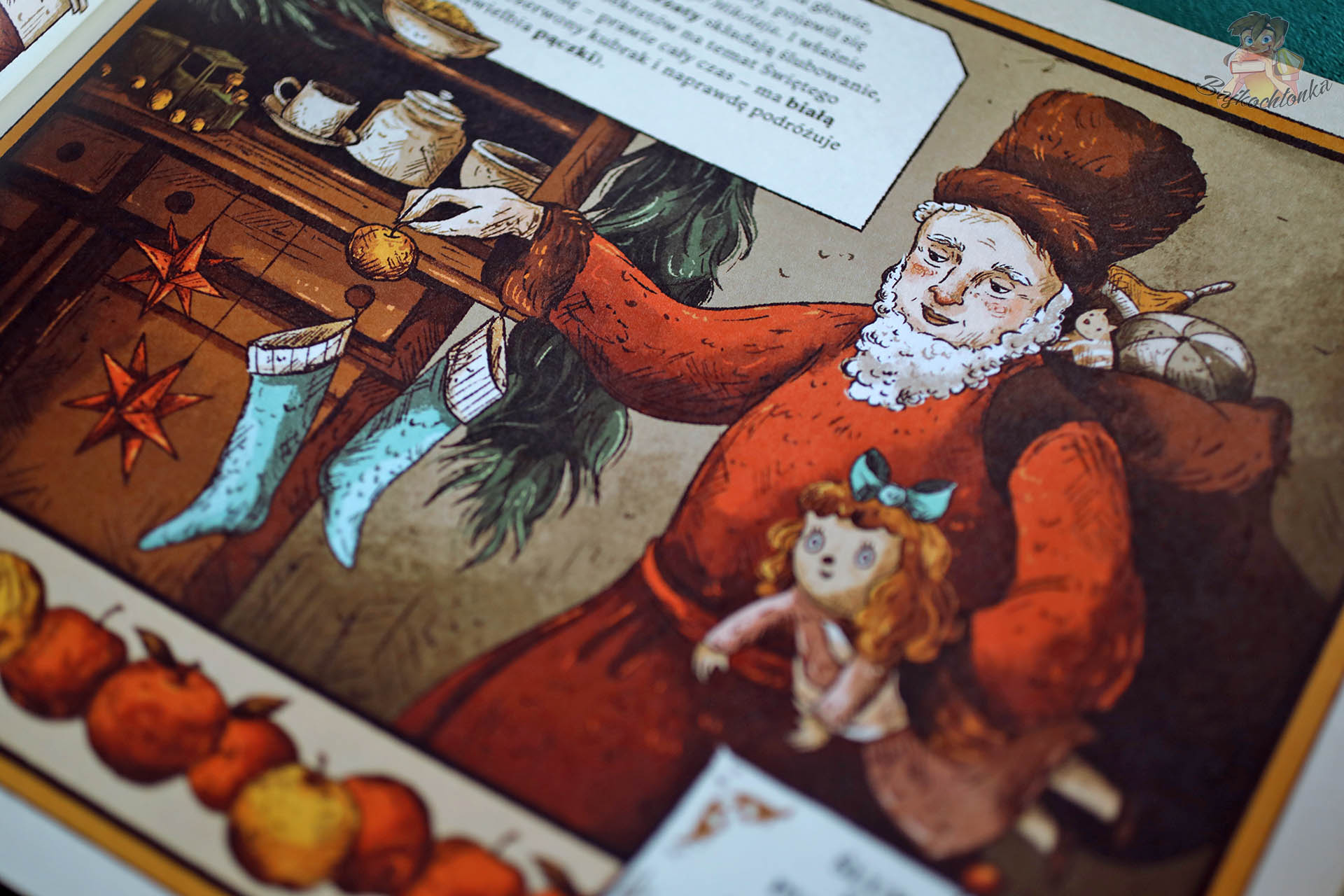 Ilustracja dawnego Świętego Mikołaja w domu, wiesza skarpety i trzyma lalkę, książka Sekrety wioski Świętego Mikołaja