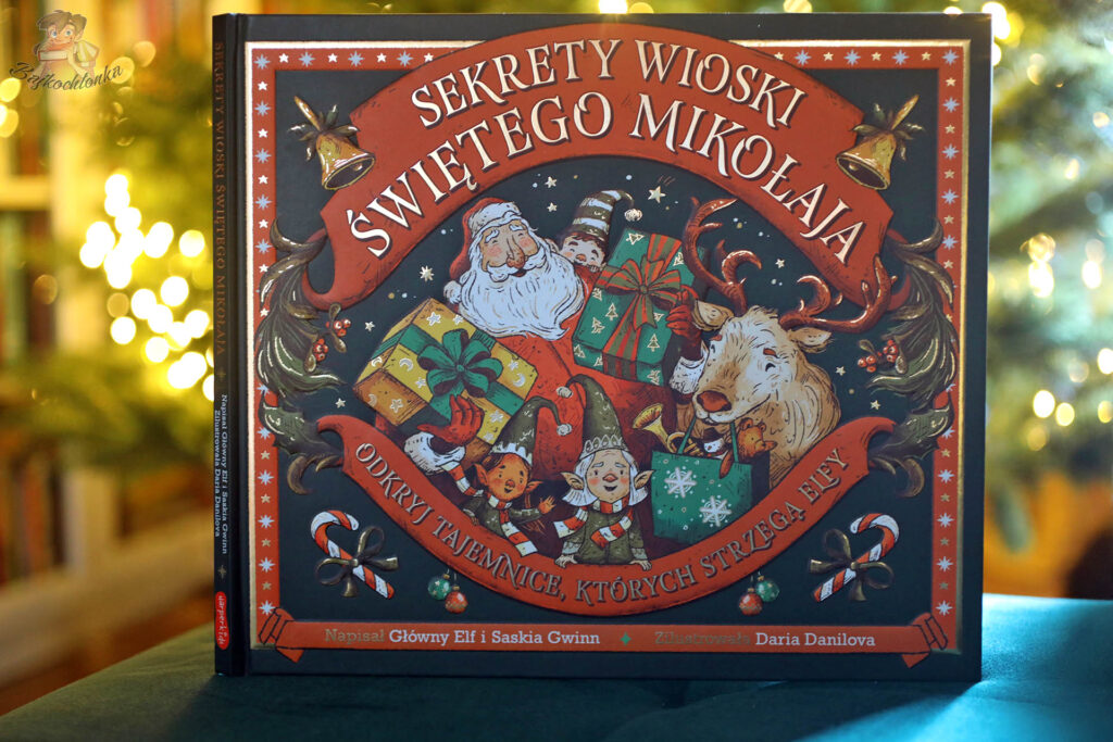 Okładka książki Sekrety wioski Świętego Mikołaja na tle choinki, świąteczna książka dla dzieci