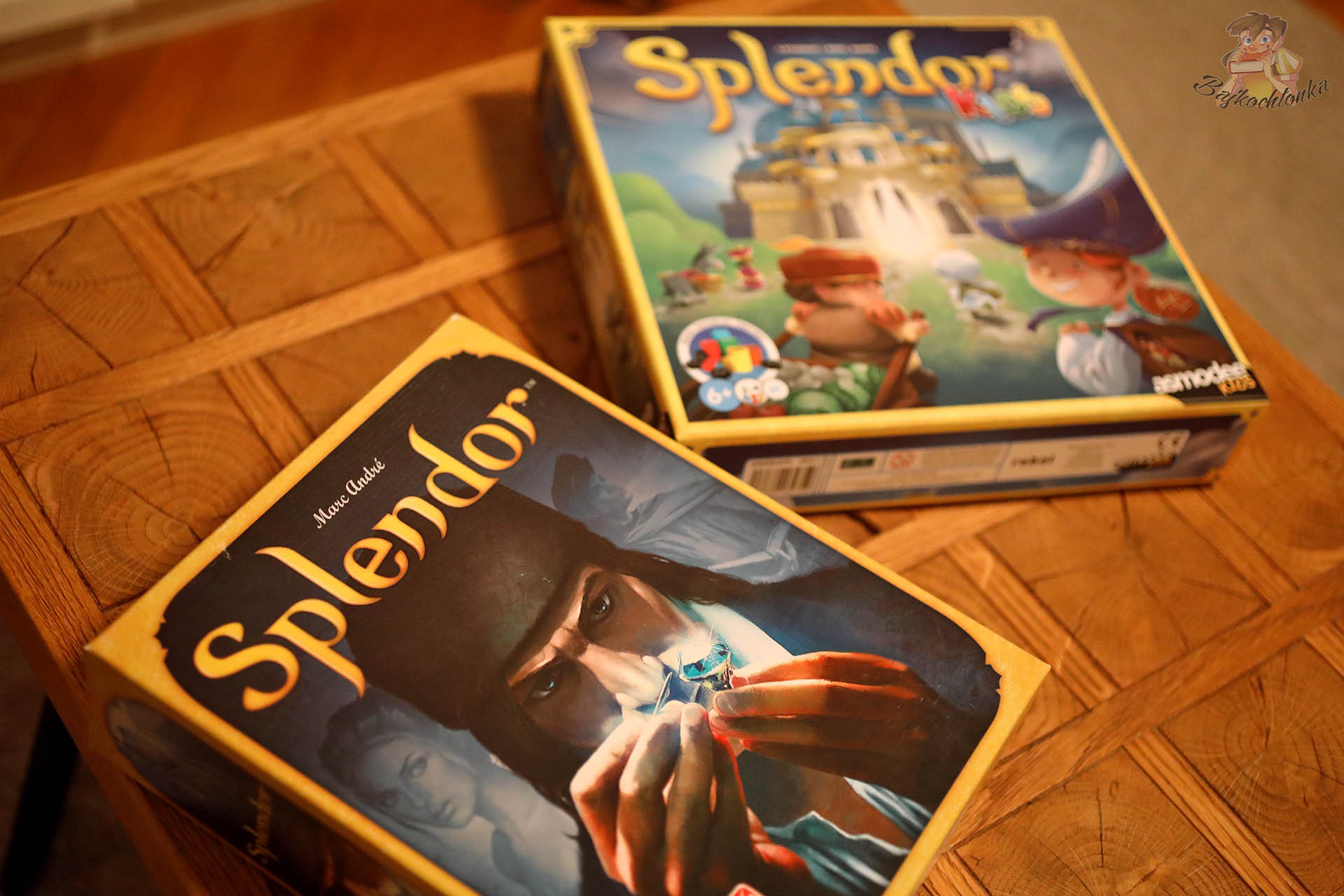Klasyczny Splendor i Splendor Kids od wydawnictwa Rebel stojące obok siebie na drewnianym stole