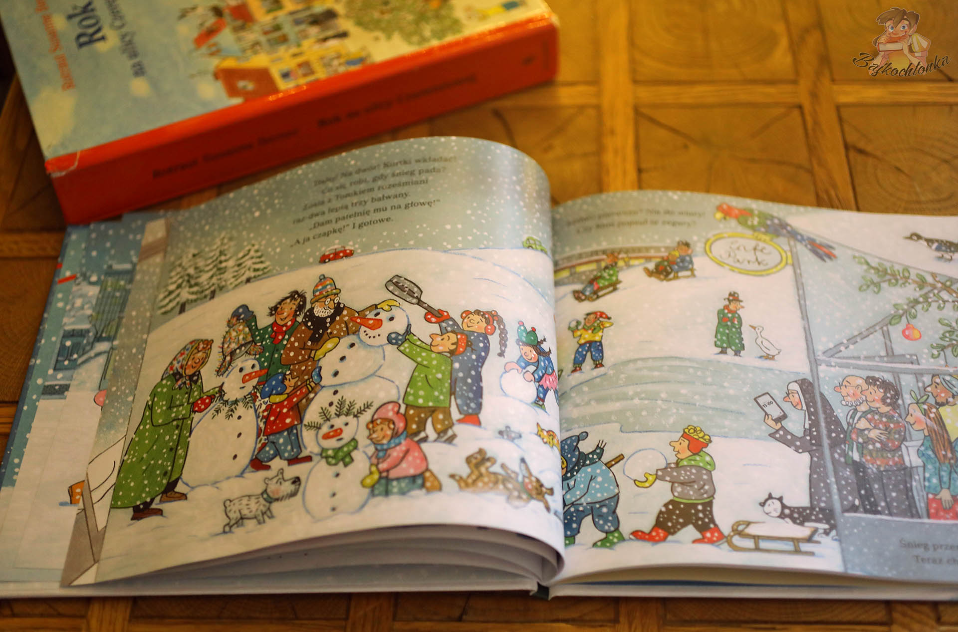 Dzieci i dorośli lepią bałwany i bawią się na śniegu w książce Święta na ulicy Czereśniowej