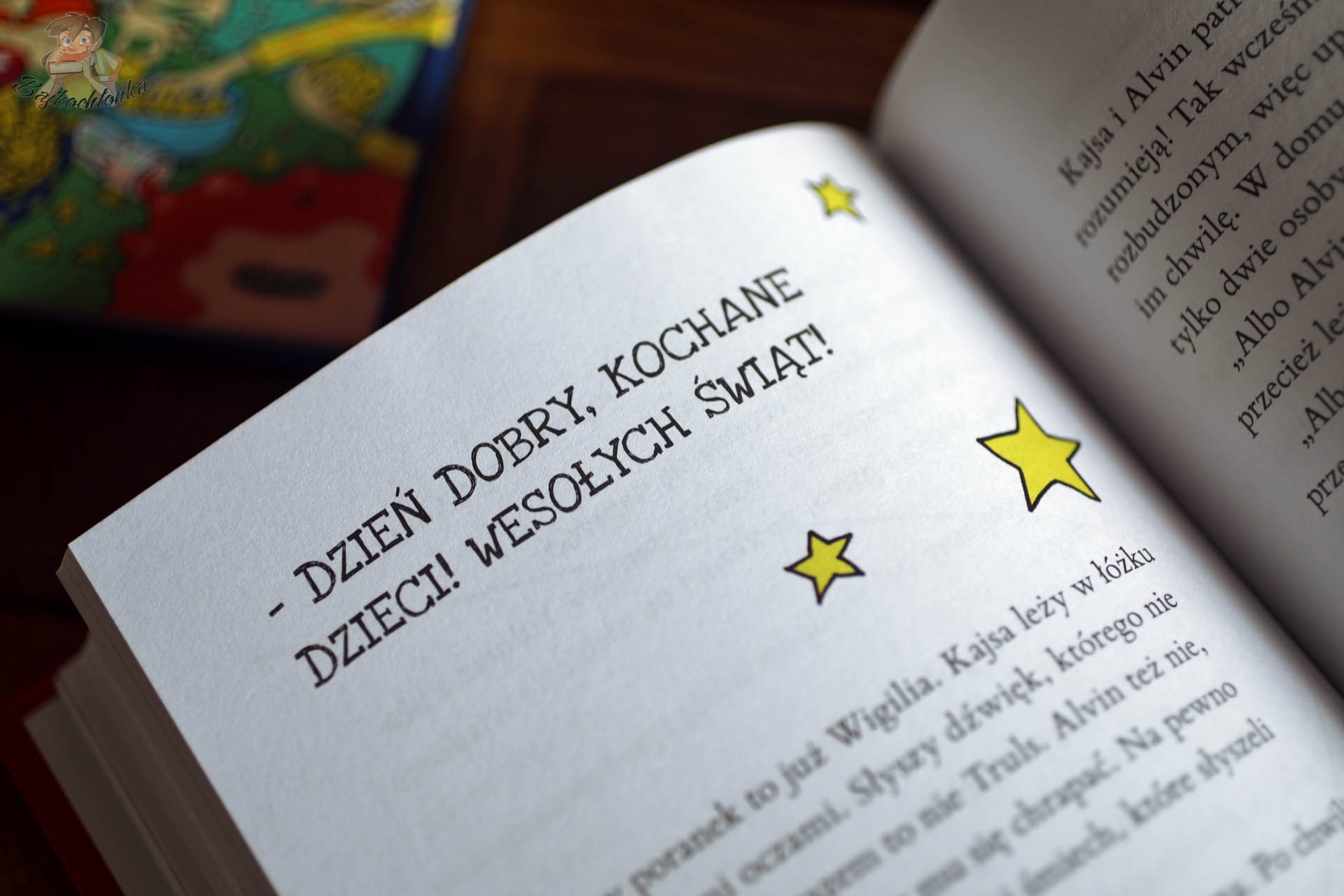 Fragment świątecznego rozdziału z książki Zwyczajna gwiazdka z rodziną Janssonów z napisem Wesołych Świąt i gwiazdkami