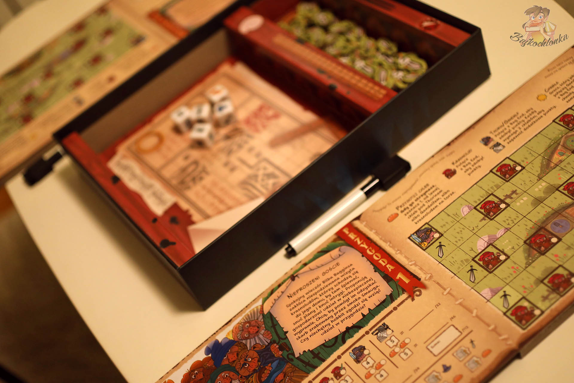 Rozłożone księgi przygód, wypraska z elementami oraz żetony gry „Hobbit: Tam i z powrotem” widziane z góry