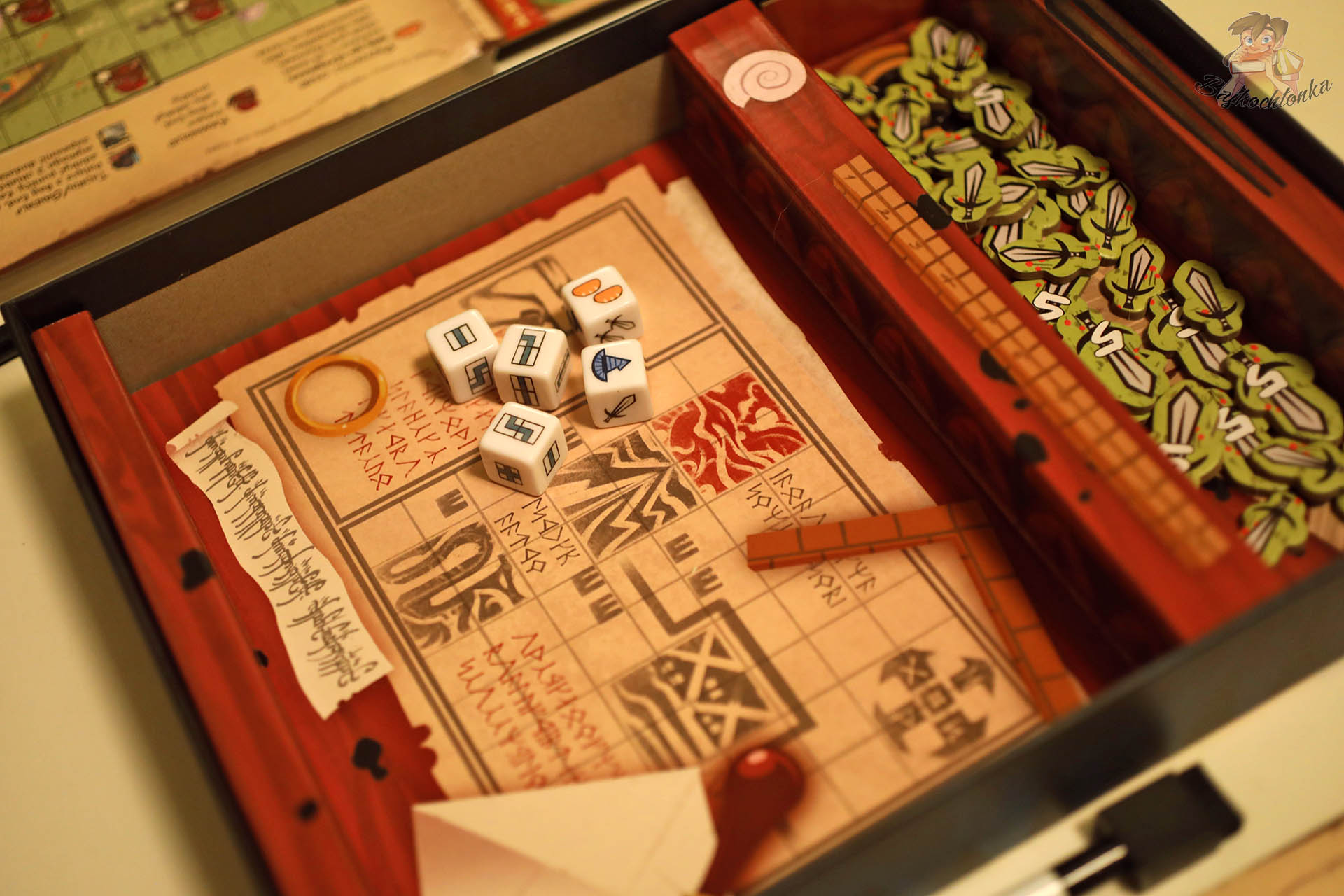 Kostki podróży oraz żetony mieczy i chleba ułożone w wyprasce pudełka gry „Hobbit: Tam i z powrotem”