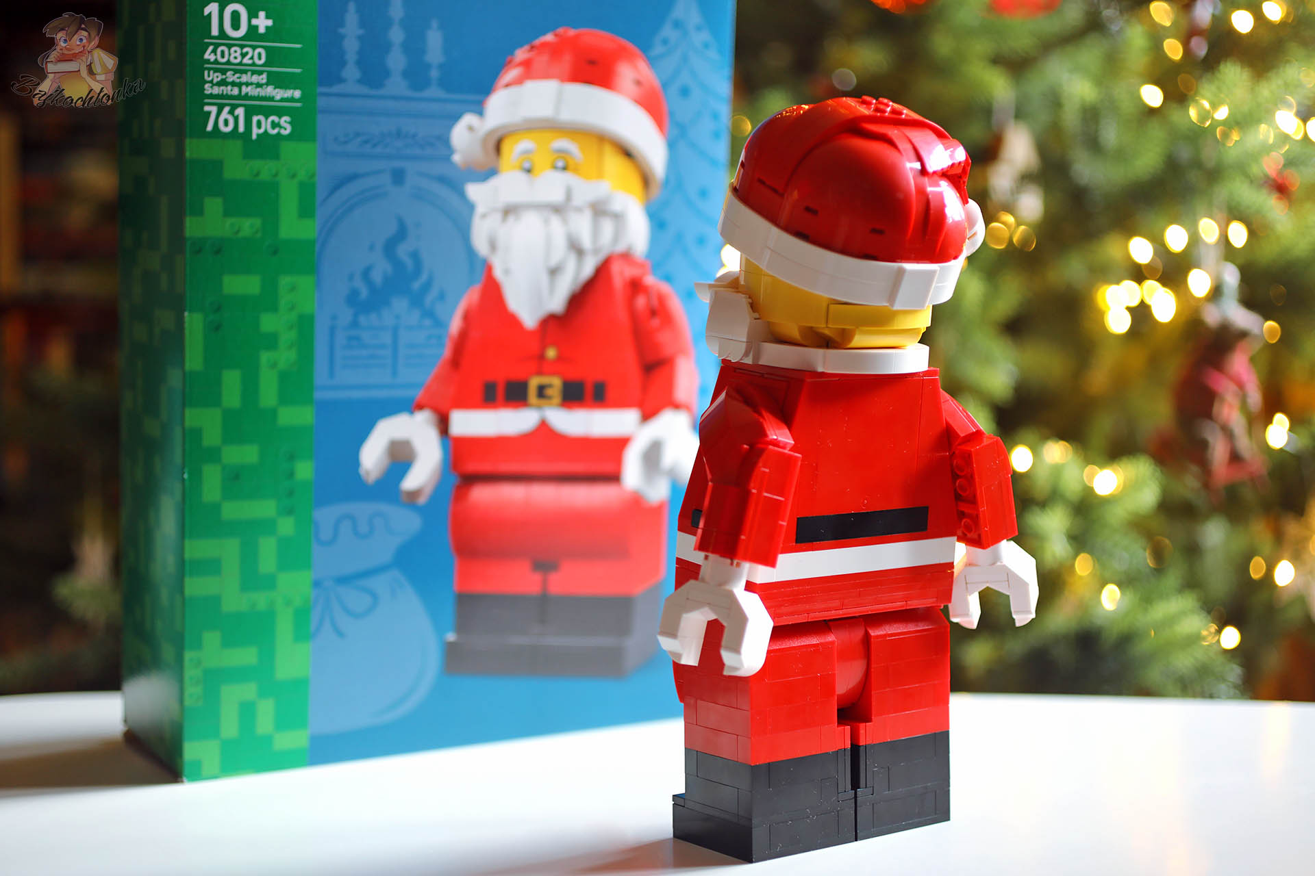 Tył powiększonej minifigurki Świętego Mikołaja LEGO 40820 na tle pudełka zestawu