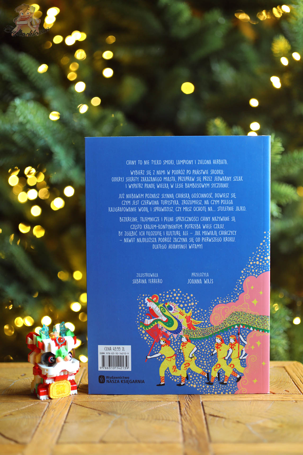 Tył okładki książki „Chiny. Od czerwonych lampionów po Zakazane Miasto” na tle świątecznego światła