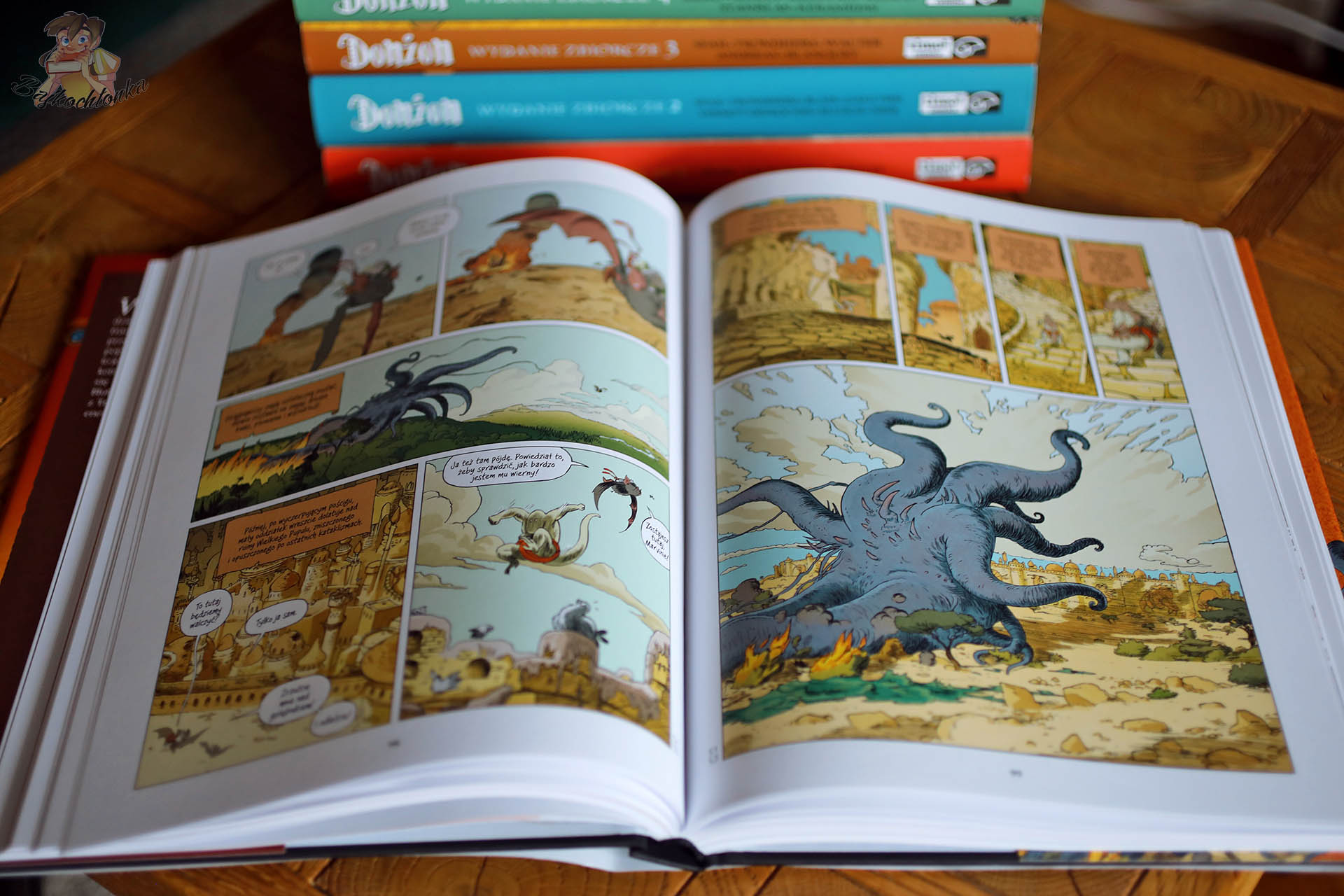 Plansza z komiksu Donżon. Wydanie zbiorcze 8 przedstawiająca scenę z cyklu Monstra 16 – dynamiczna walka z ogromnym potworem na tle pustynnego miasta.