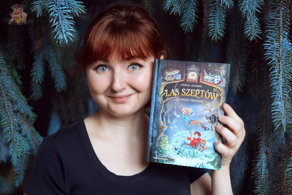 Autorka recenzji Bajkochłonka trzyma książkę Zaginiony profesor. Las Szeptów. Tom 2 w klimatycznej leśnej aranżacji