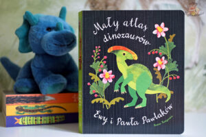 Okładka książki Mały atlas dinozaurów Ewy i Pawła Pawlaków – ilustracja zielonego dinozaura wśród roślin