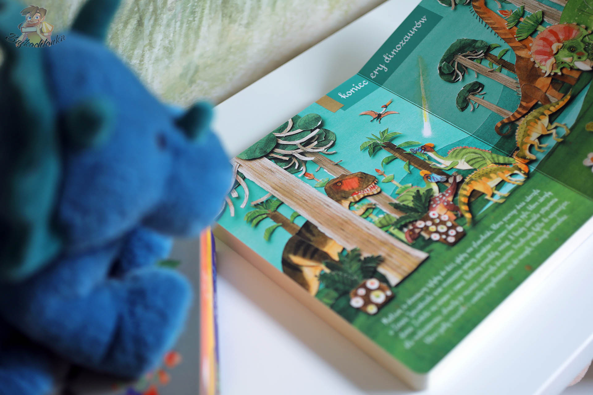 Rozkładówka książki Mały atlas dinozaurów Ewy i Pawła Pawlaków – ilustracja prehistorycznego lasu z tyranozaurem i pterozaurem