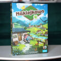 Okładka gry planszowej Naklejkowo wydawnictwa Rebel – kooperacyjne budowanie miasteczka