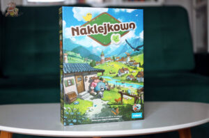 Okładka gry planszowej Naklejkowo wydawnictwa Rebel – kooperacyjne budowanie miasteczka