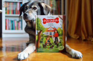 Książka „Psia Chatka. Szczeniaki w potrzebie” obok psa – historia inspirowana prawdziwymi wydarzeniami o adopcji zwierząt
