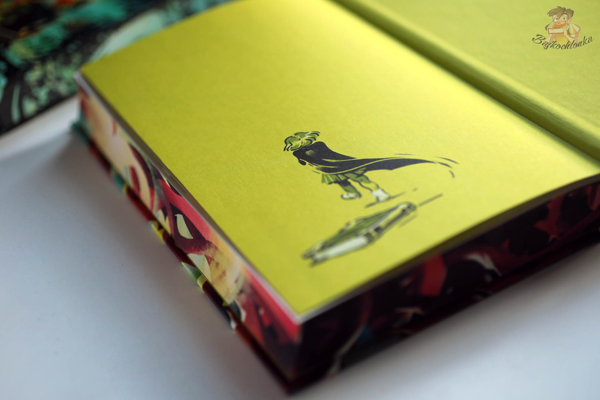 Zbliżenie na żółtą wyklejkę wydania Harry Potter i Komnata Tajemnic z ilustracją postaci i różdżki