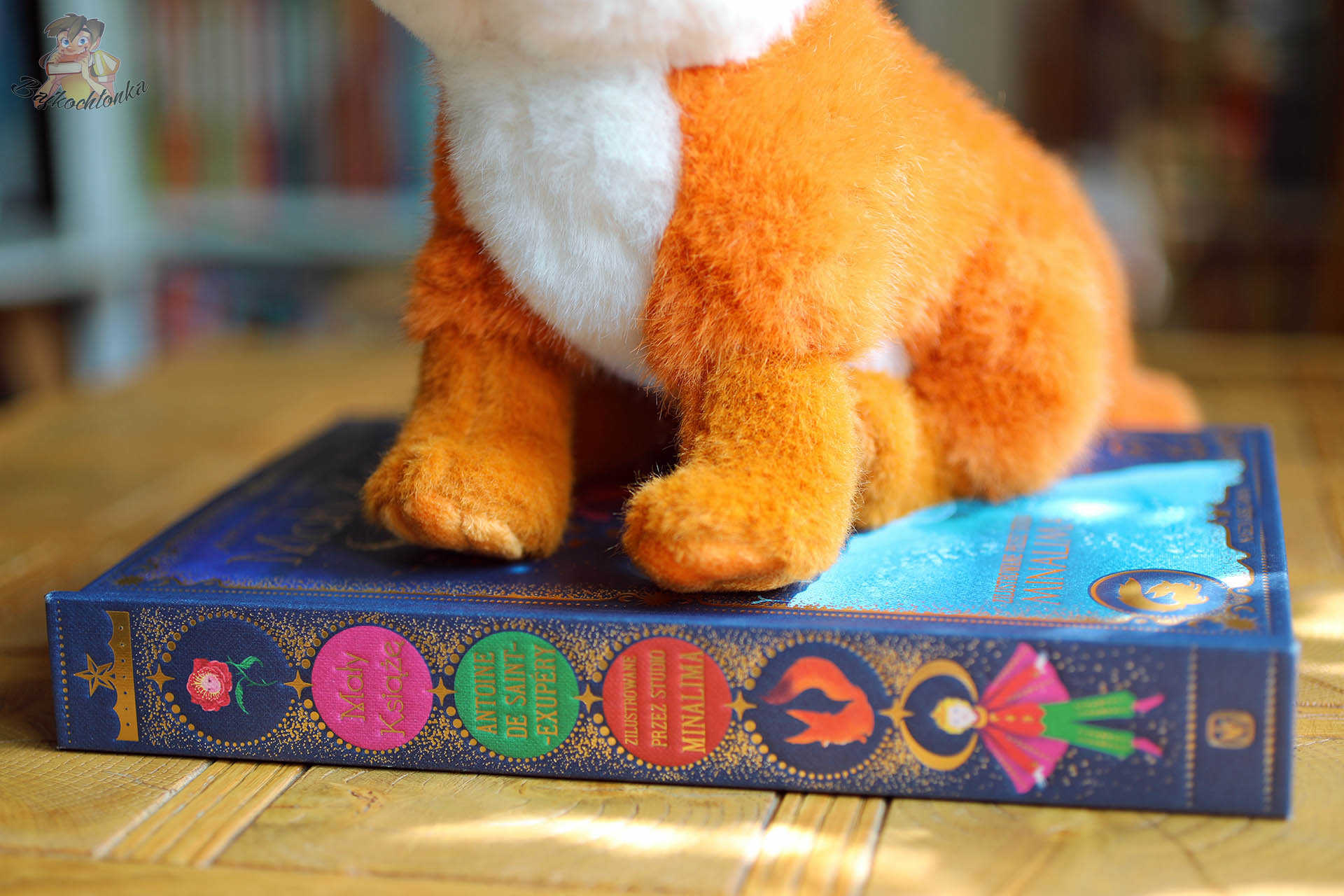 pluszowy lisek stojący na grzbiecie książki Mały Książę MinaLima