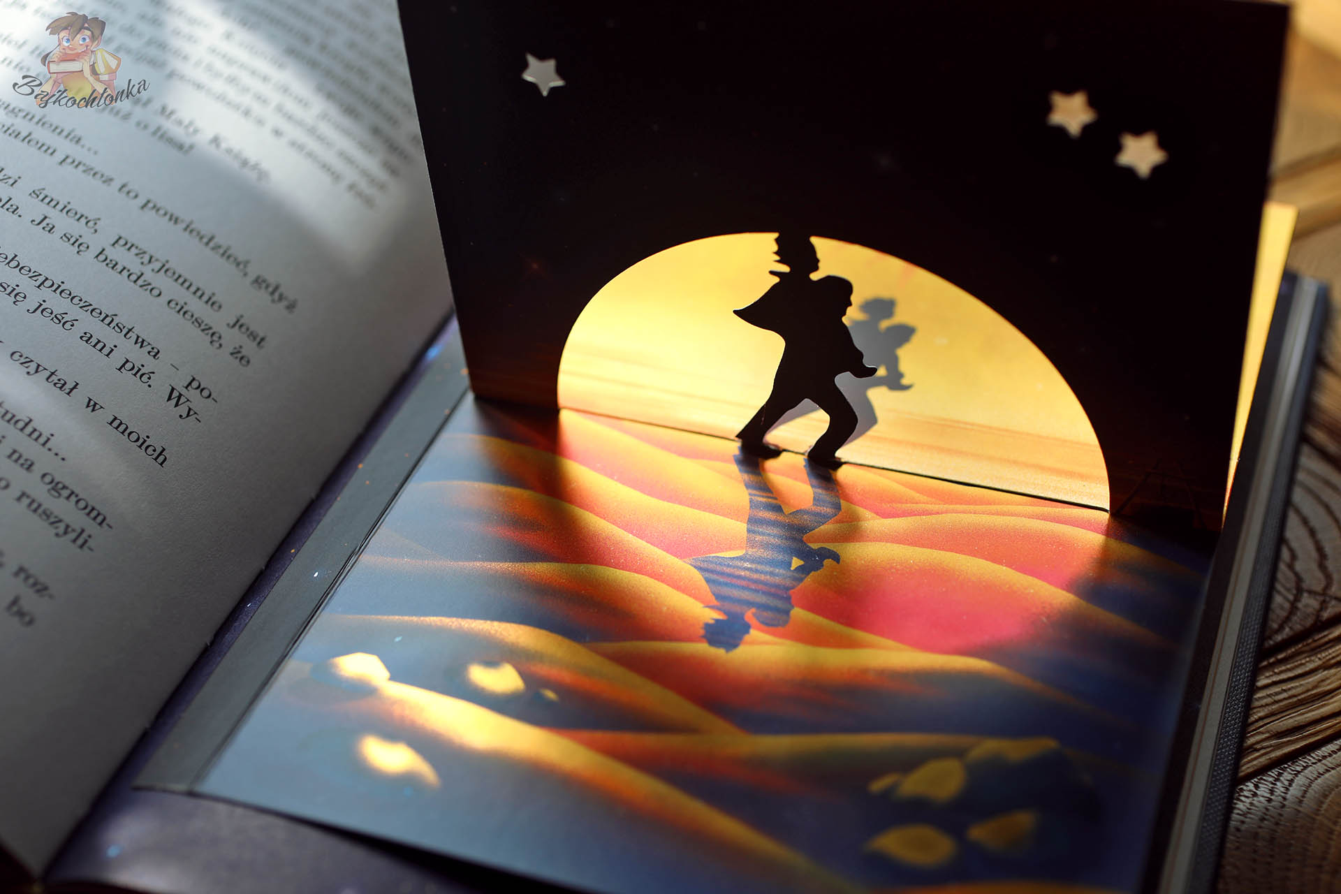 przestrzenny element w książce Mały Książę MinaLima – sylwetka Małego Księcia na tle pustyni i zachodu słońca