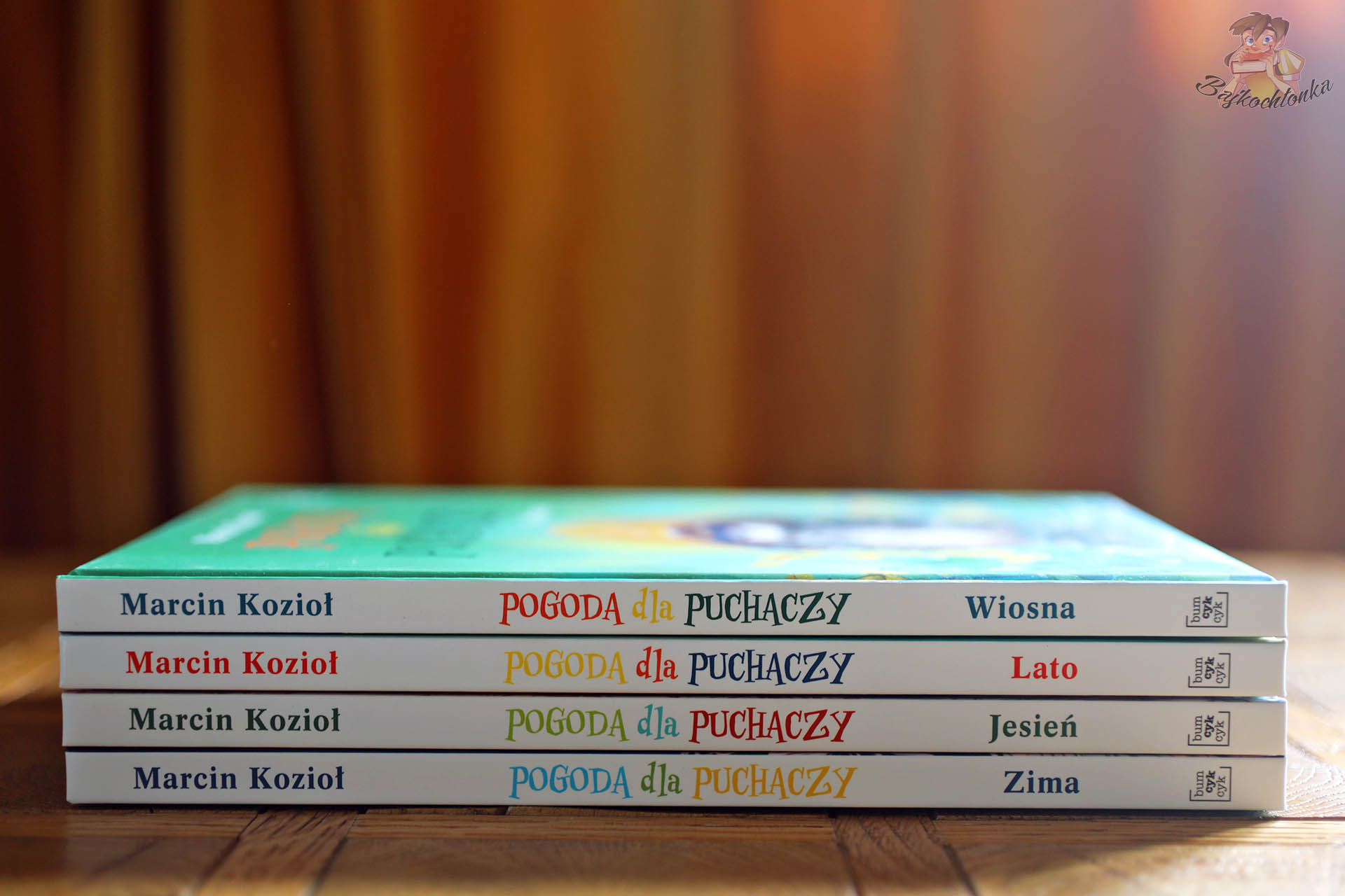 Grzbiety książek z serii Pogoda dla puchaczy Marcina Kozioła ułożone w stos