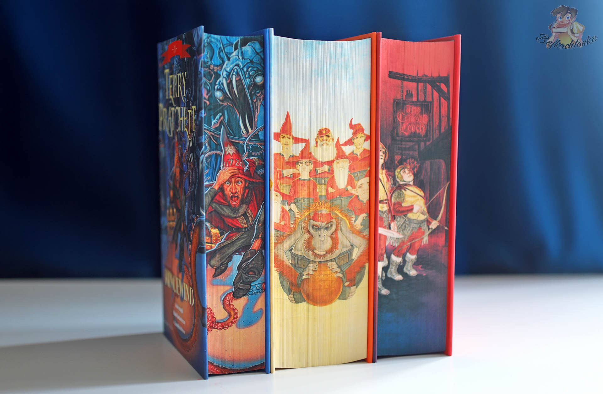 Wydania Terry’ego Pratchetta z barwionymi brzegami ustawione pionowo, w tym Straż miejska. Tom 1