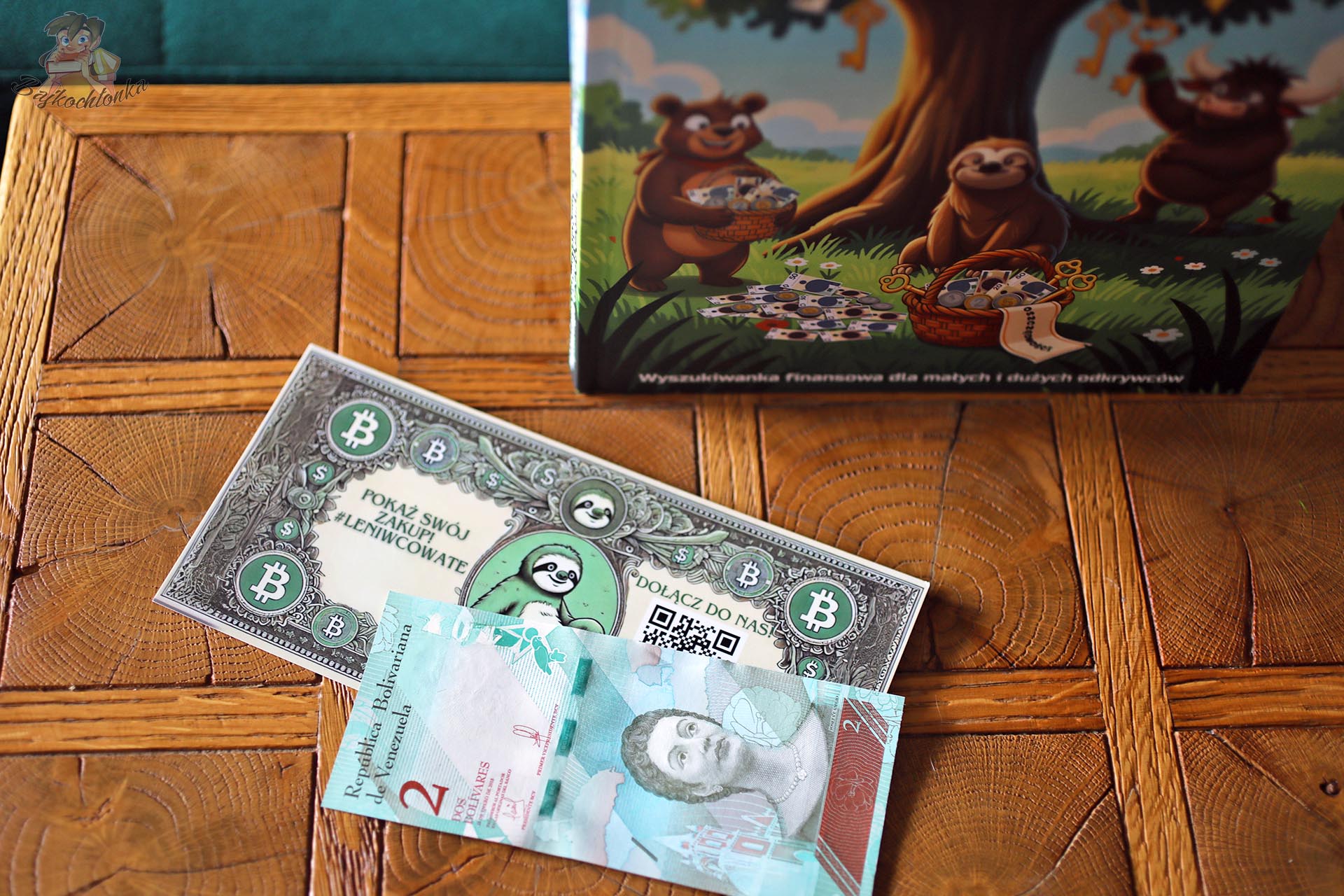 Egzemplarz książki Leniwcowe Przygody z banknotem i zakładką dołączonymi do wyszukiwanki finansowej dla dzieci