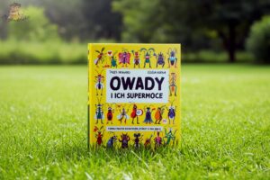 Okładka książki Owady i ich supermoce Julesa Howarda i Gosi Herby sfotografowana na trawie, z kolorowymi ilustracjami owadów.