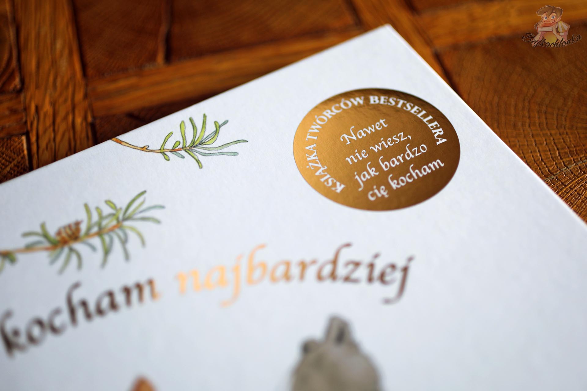 Zbliżenie na złote uszlachetnienie okładki książki Wszystkich was kocham najbardziej, wydania twórców bestsellera Nawet nie wiesz, jak bardzo cię kocham.
