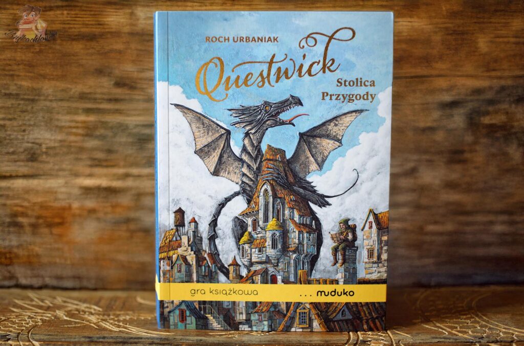 Okładka gry książkowej „Questwick. Stolica Przygody” Rocha Urbaniaka z ilustracją smoka nad miastem