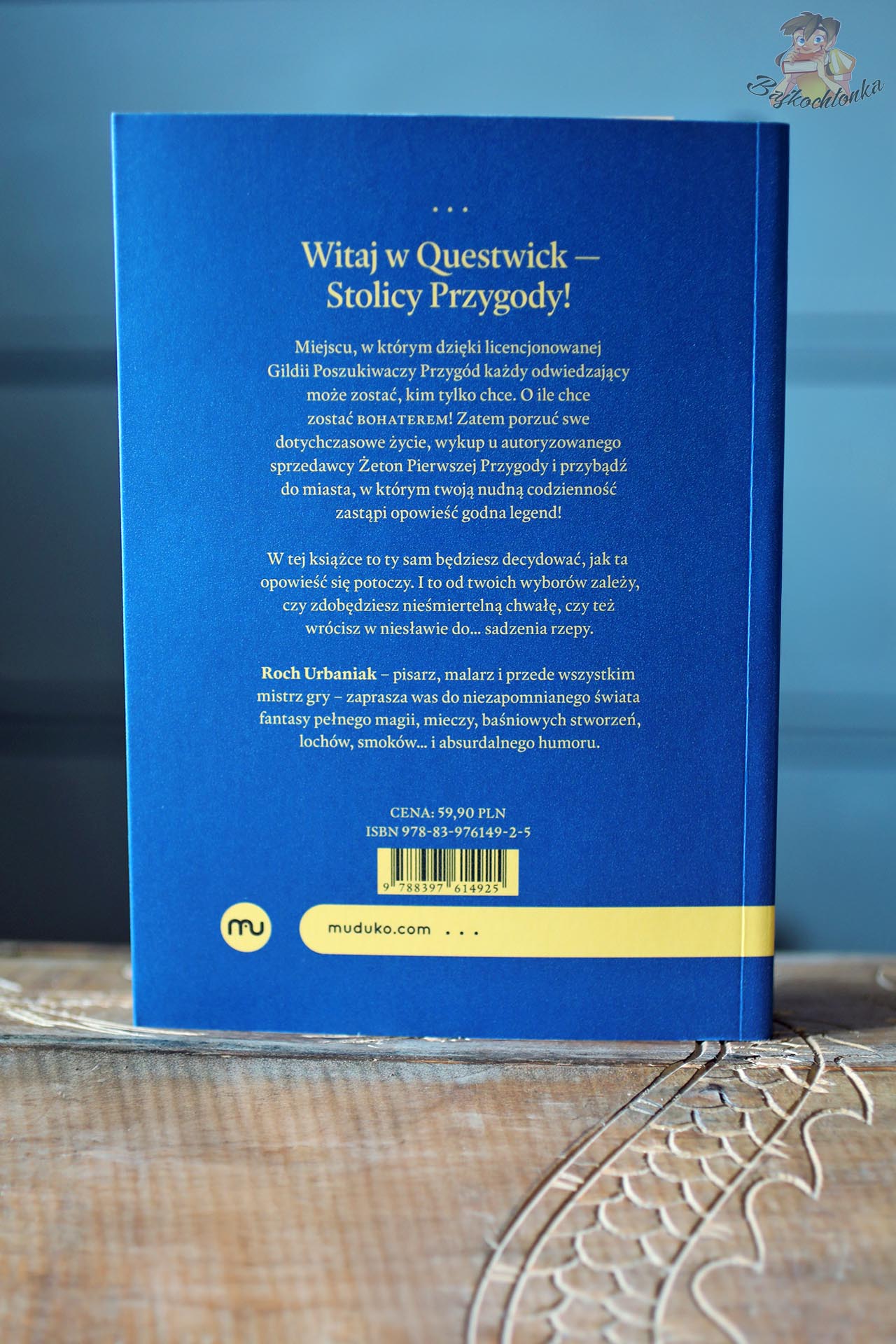 Tylna okładka książki „Questwick. Stolica Przygody” z opisem gry paragrafowej Rocha Urbaniaka