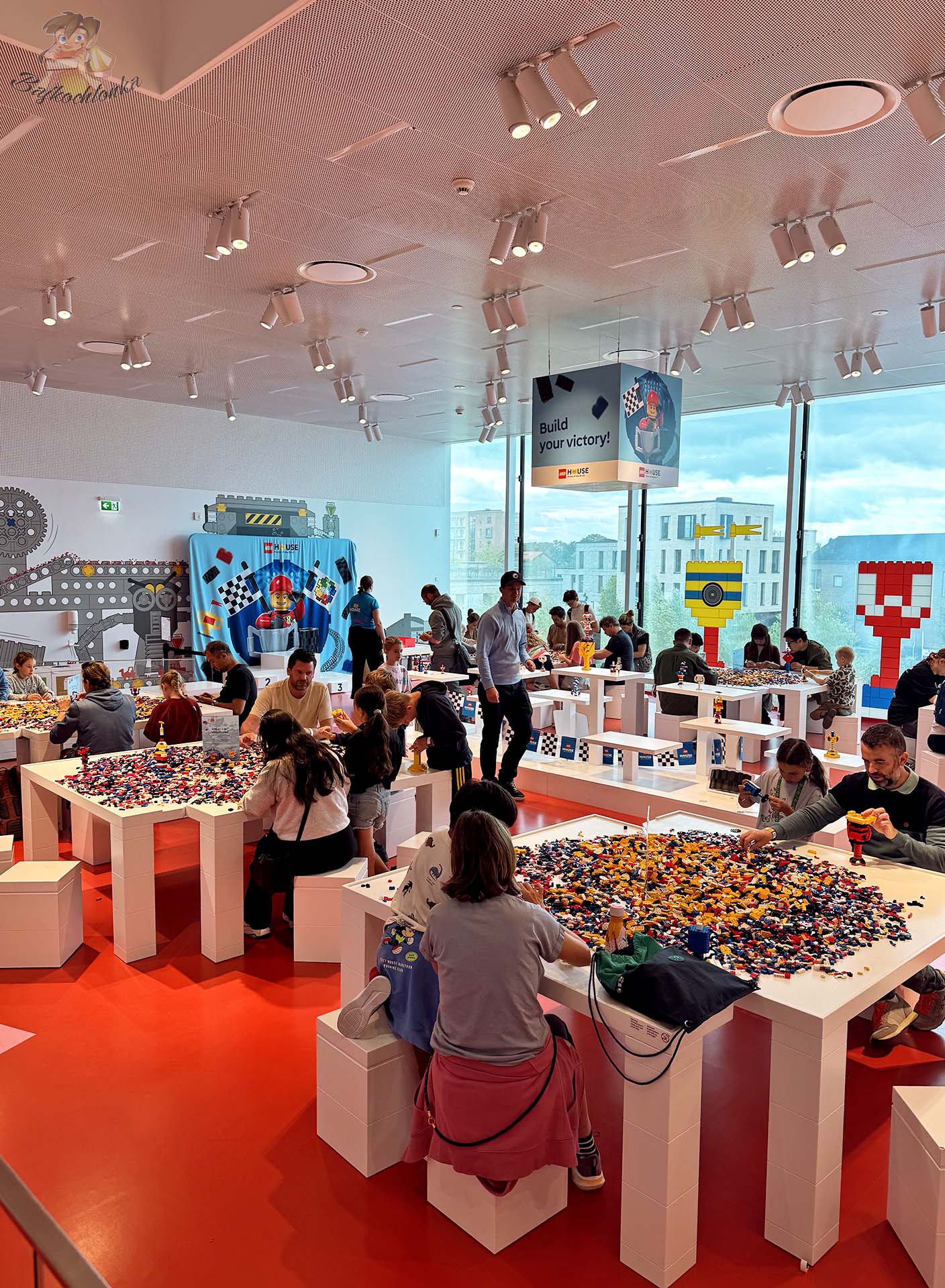 Rodziny budujące własne konstrukcje z klocków w interaktywnej strefie LEGO House