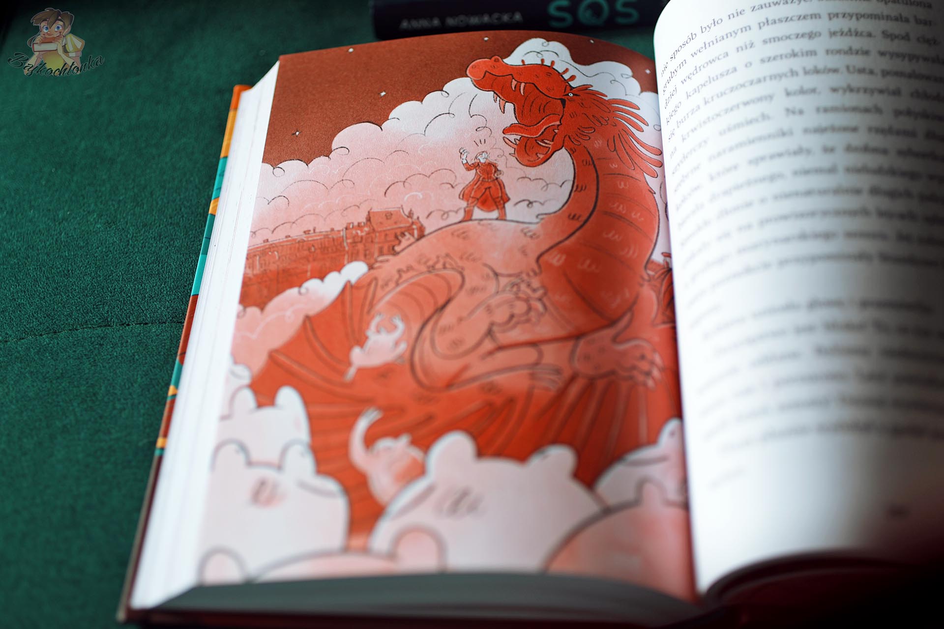 Duży czerwony smok na tle zabudowań Krakowa – ilustracja Oli Bylicy z powieści fantasy KLOPS Anny Nowackiej.