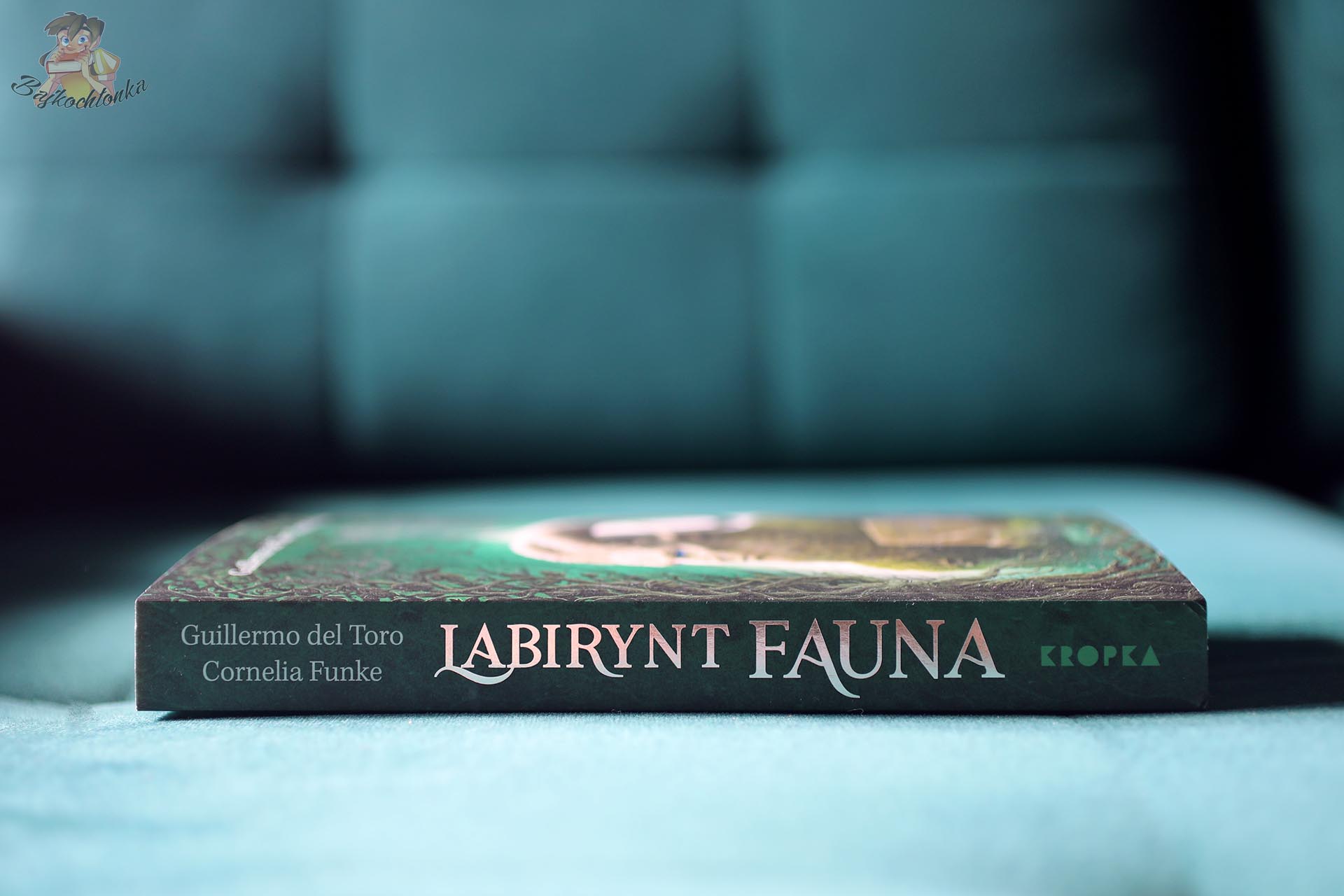 Grzbiet książki Labirynt Fauna w miękkiej oprawie, z nazwiskami Guillermo del Toro i Cornelii Funke oraz logo Kropki.