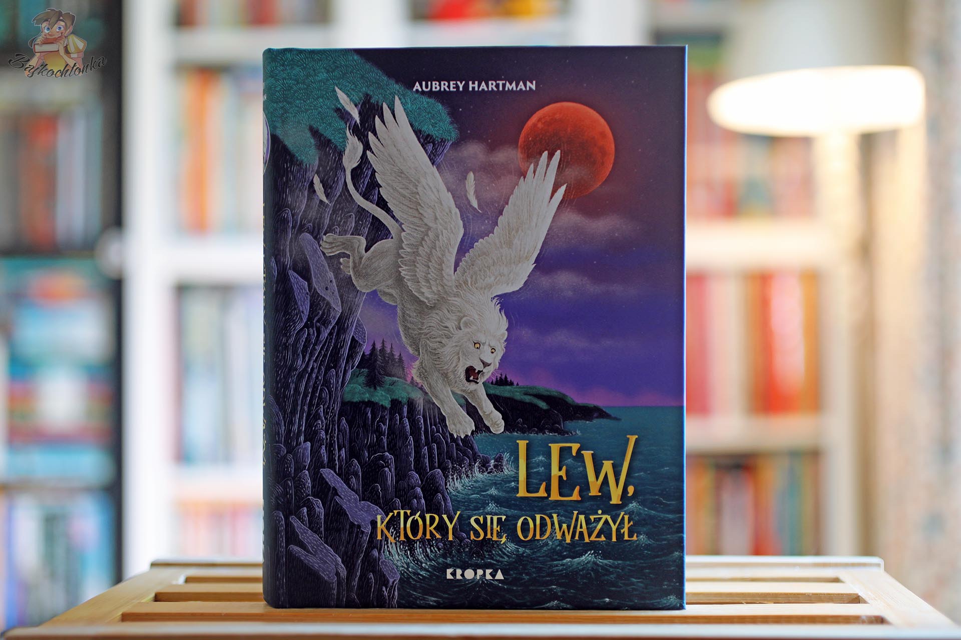 Okładka książki Lew, który się odważył Aubrey Hartman z ilustracją białego skrzydlatego lwa