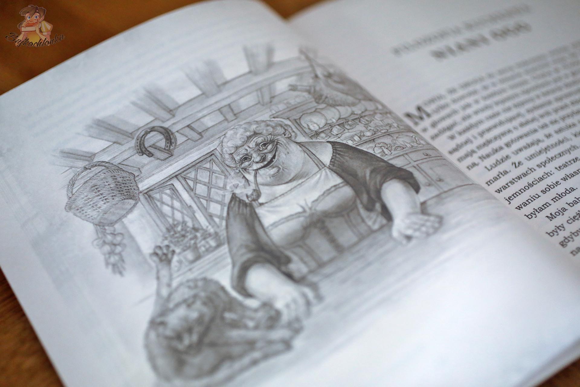 Czarno-biała ilustracja Paula Kidby’ego przedstawiająca uśmiechniętą Nianię Ogg z fajką w kuchni