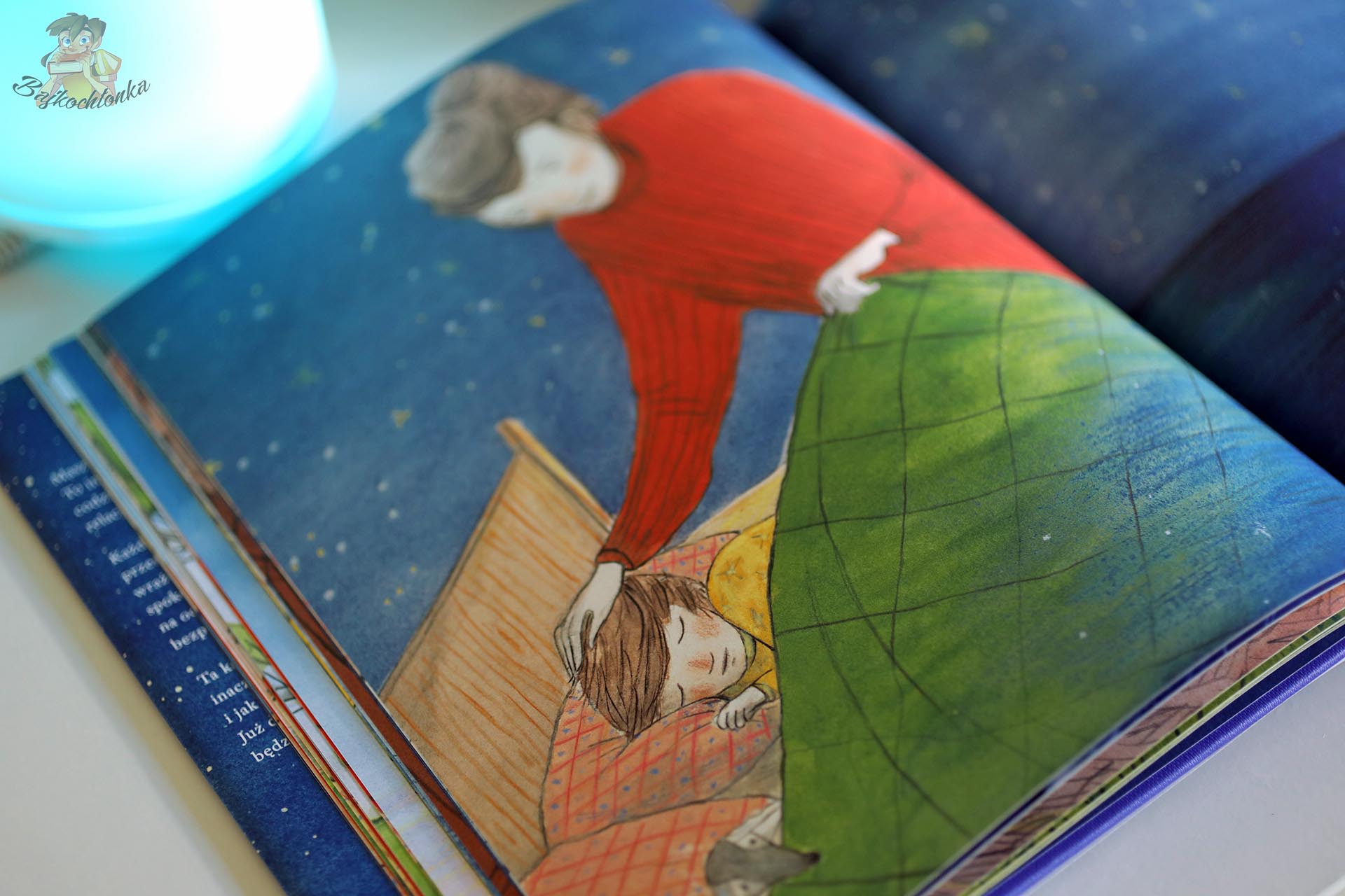 Ilustracja z książki Nim powiesz dobranoc – mama głaszcze po głowie zasypiającego chłopca przykrytego zieloną kołdrą