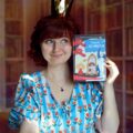 Kobieta w królewskiej koronie prezentuje książkę Potyczki z Arcymagiem Reginy Golińskiej-Barancewicz na tle domowej biblioteczki.